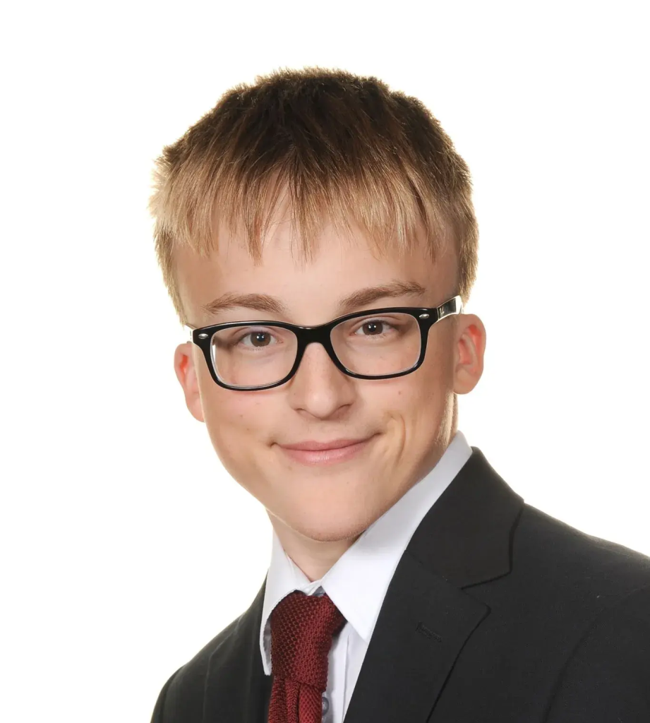 A photograph of Eddie, the service provider which this website revolves around. Eddie is smiling, wearing a black suit, white shirt, and red tie. Eddie has black glasses.