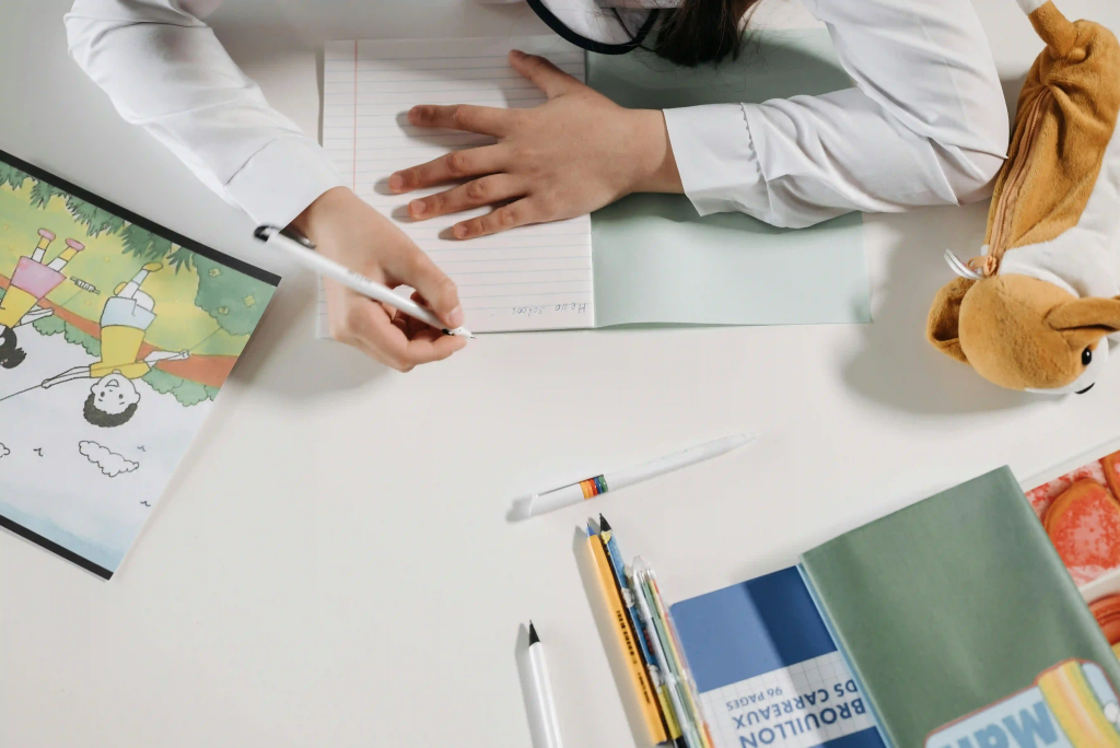 Image showing a child being tutored, tuition, working on a book with other educational items scattered around.